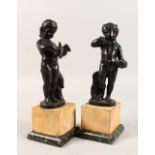 AFTER THE ANTIQUE. A PAIR OF BRONZES OF CUPIDS on marble plinths. 11.5ins high.