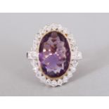A 9CT GOLD LARGE AMETHYST AND DIAMOND OVAL RING.