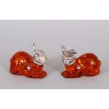 A SMALL PAIR OF AMBER RABBITS, with plated heads.