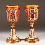 A PAIR OF BOHEMIAN GOBLETS, pink ground edged in gilt, with panels of flowers. 8ins high (AF).