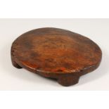 AN EARLY ETHNIC CIRCULAR WOODEN LOW STOOL OR TABLE with four feet, carved out of one piece of