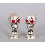 A MINIATURE PAIR OF SKULL SALT AND PEPPERS.