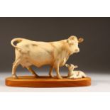 A BESWICK PORCELAIN CHAROLAIS COW AND CALF on a wooden base. 10ins wide.