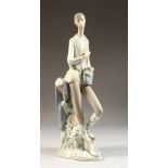 A TALL LLADRO FIGURE OF A YOUNG MAN standing beside a tree stump. 15ins high.