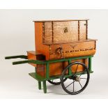 AN UNUSUAL LATE 19TH CENTURY OAK MUSICAL BOX MODELLED AS A BARREL ORGAN, mounted on a green