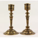 A PAIR OF TURNED BRASS CANDLESTICKS, with engraved niello decoration. 7ins high.