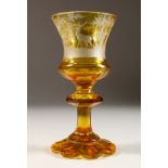 A BOHEMIAN AMBER CUT GOBLET, engraved with deer in a wood. 7ins high.