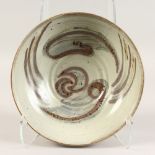 A PALE BROWN GLAZE POTTERY BOWL with a swirl, 11ins diameter.