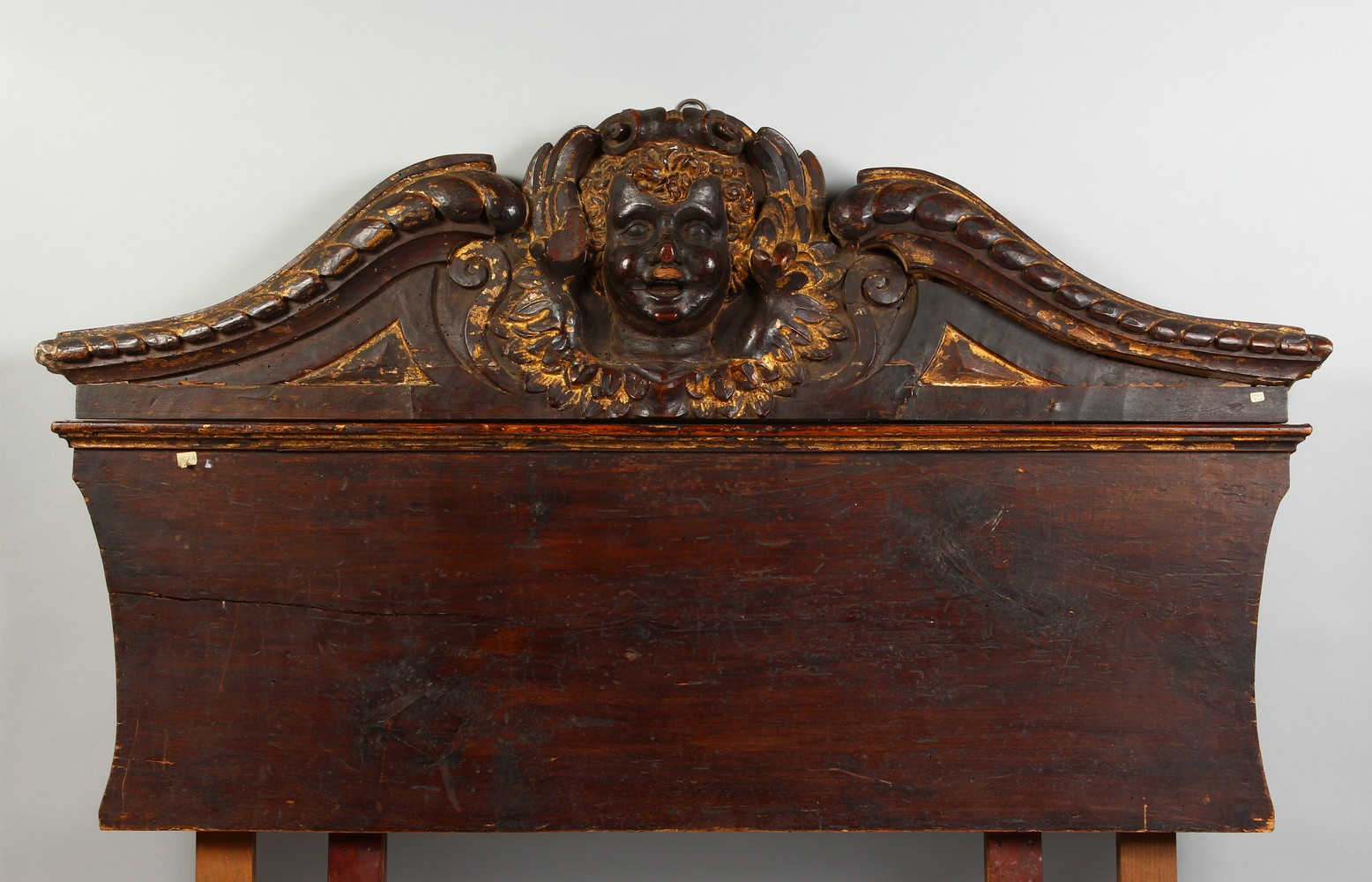 A 17TH-18TH CENTURY ITALIAN CARVED WOOD AND GILDED HEADBOARD carved with a mask. 45ins long x