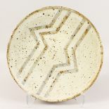 A CREAM POTTERY CIRCULAR DISH with zig zag pattern. 15ins diameter.