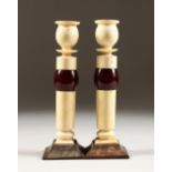 A PAIR OF ART DECO IVORY AND EBONY CANDLESTICKS. 7ins high.