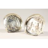 A PAIR OF VICTORIAN SILVER CIRCULAR DISH, repousse with man and a building. 8cms diameter. London