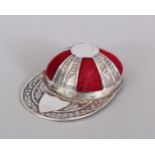 A NOVELTY SILVER JOCKEY CAP PIN CUSHION.