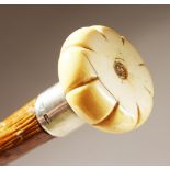 AN EARLY 19TH CENTURY WALKING STICK, with carved ivory pommel and silver collar. 35ins long.