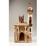 A PERUVIAN PAINTED POTTERY CHURCH, with bell tower, two clocks and figures. 54cms high x 23cms