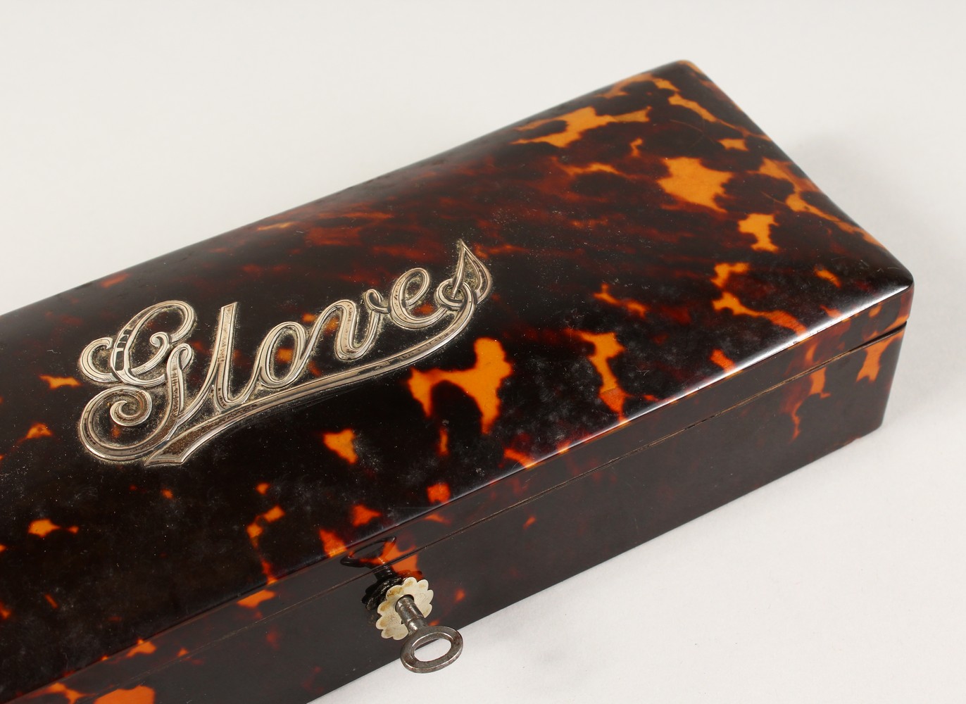 A VICTORIAN RECTANGULAR TORTOISESHELL GLOVE BOX, the lid with "Gloves" in silver. 26cms long.