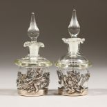 A SMALL PAIR OF GLASS SCENT BOTTLES AND STOPPERS, in silver stands. 6cms high.