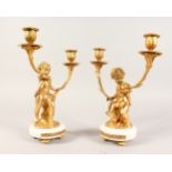 A GOOD PAIR OF ORMOLU AND WHITE MARBLE TWO-LIGHT CUPID CANDELABRA, on circular marble bases. 11ins