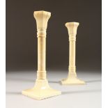 A PAIR OF ART DECO IVORY CANDLESTICKS on square bases. 7.5ins high.