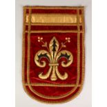 A RED VELVET PENNANT, embroidered with a single fleur-de-lys design. 20ins x 13ins.