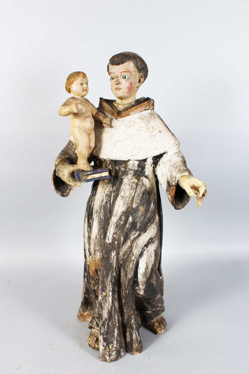 A 17TH-18TH CENTURY ITALIAN CARVED WOOD AND PAINTED STANDING FIGURE OF A MONK holding a child on a