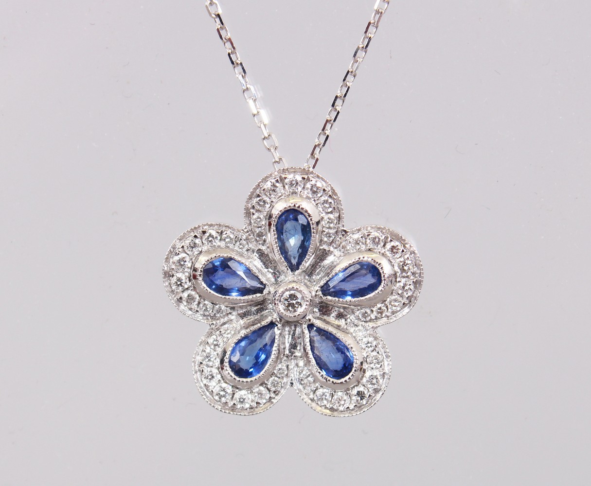 AN 18CT WHITE GOLD FLOWER SHAPED SAPPHIRE AND DIAMOND PENDANT NECKLACE OF 1.5cts.