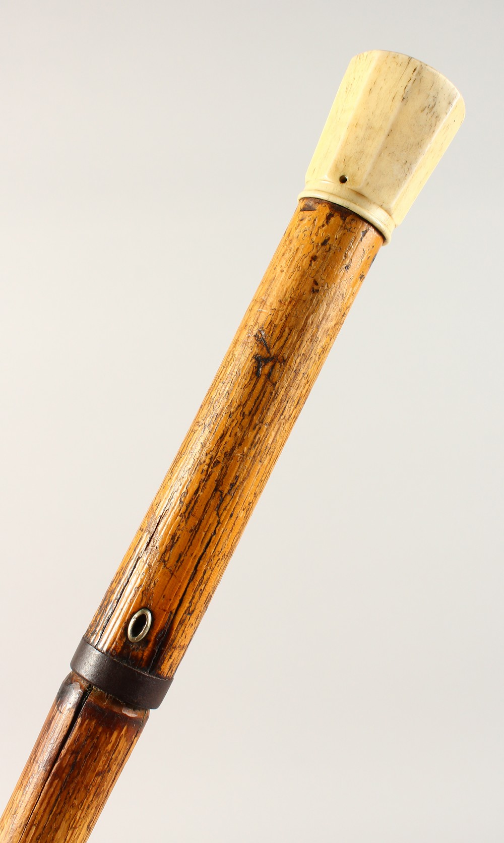 A 19TH CENTURY BAMBOO DAGGER CANE, with ivory pommel. 37ins long.