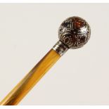 A 19TH CENTURY RHINO HORN SWAGGER STICK, with gold and silver inlaid ball shape pommel. 24ins long