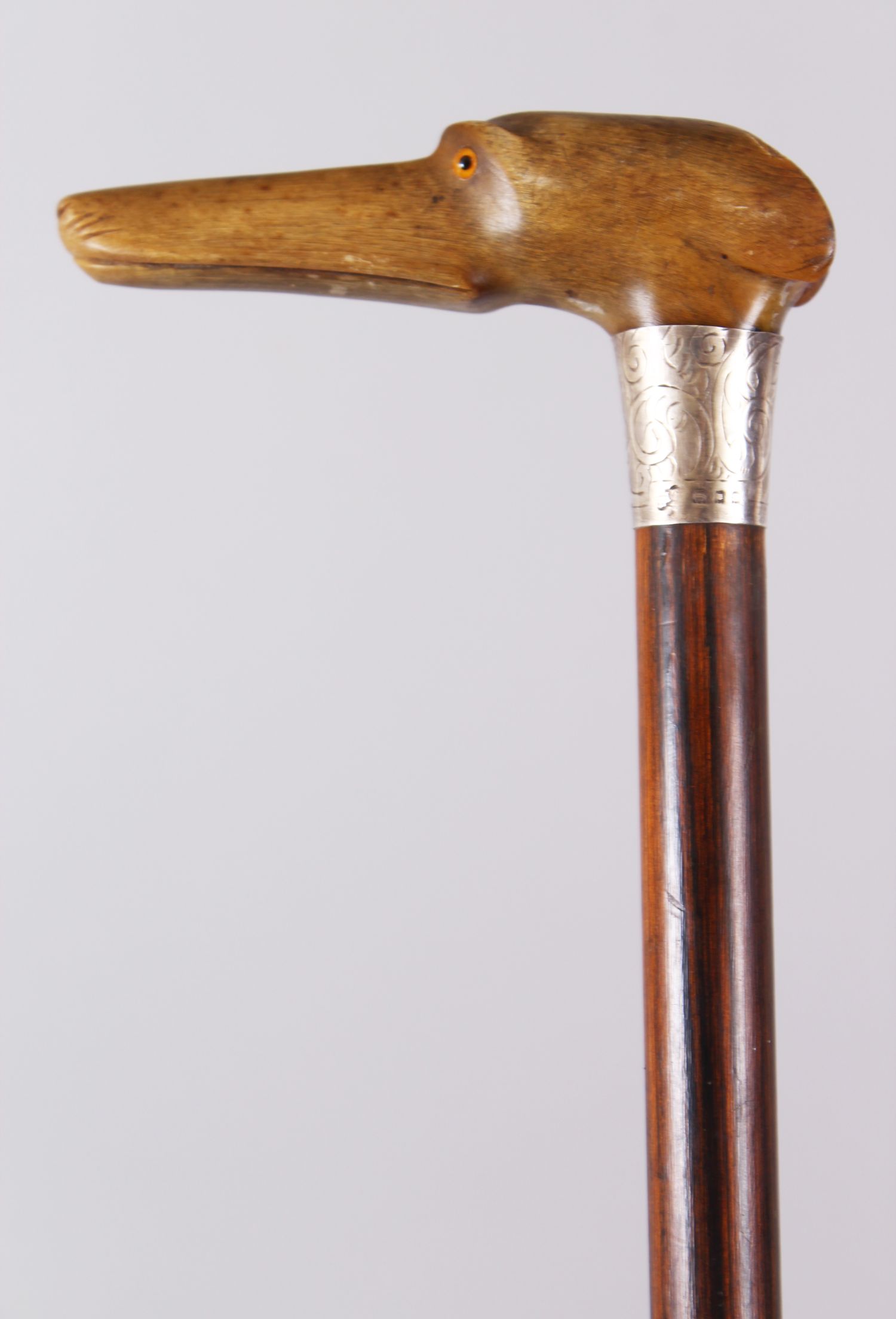 A RHINO HANDLED CANE, carved as a dog with silver band, 93cm long.