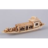 A JAPANESE IVORY OKIMONO OF A BOAT, carved with various characters, Meiji period, 7.5cm high, 23cm