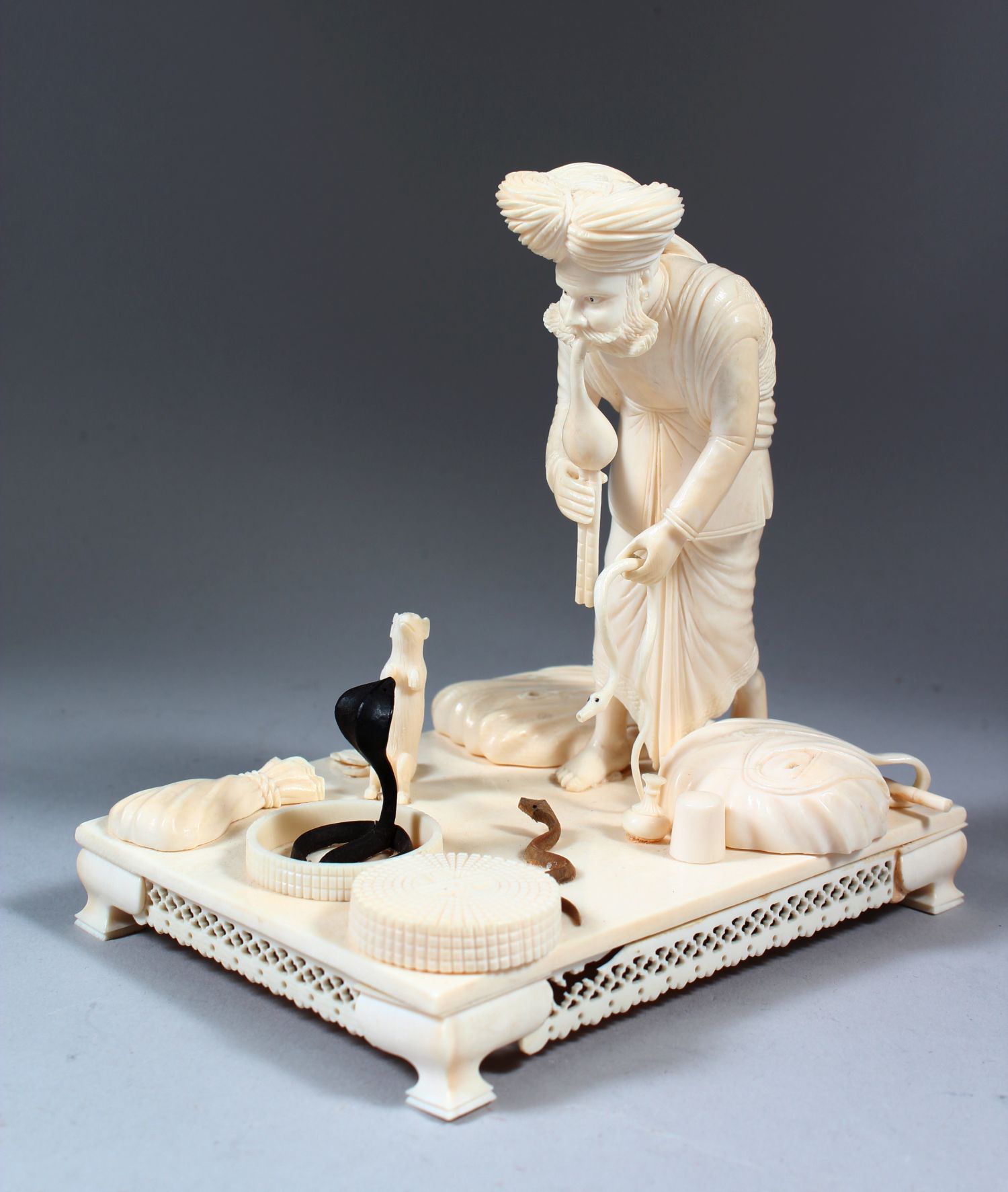 A GOOD 19TH CENTURY INDIAN CARVED IVORY GROUP OF A SNAKE CHARMER with three snakes, standing on a