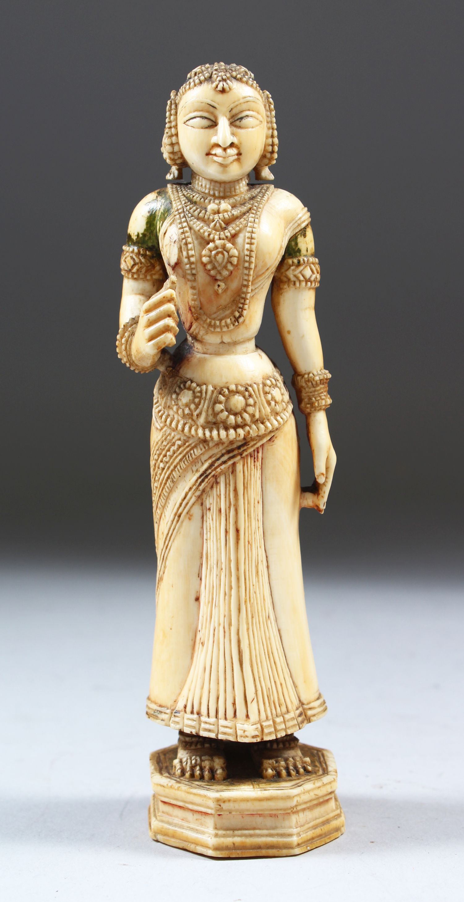 A 17TH-18TH CENTURY INDIAN POLYCHROME CARVED IVORY FIGURE of a young lady standing on an octagonal