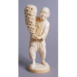 A GOOD QUALITY JAPANESE IVORY OKIMONO, a man holding a pot of draping chrysanthemums, green seal