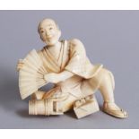 A GOOD JAPANESE IVORY OKIMONO depicting a man kneeling holding a fan and various other utensils,