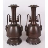 A PAIR OF JAPANESE BRONZE TWO HANDLED VASES, with mask handles. 36 cm high