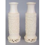 A PAIR OF EARLY 20TH CENTURY CHINESE IVORY VASES, each carved with dragons amidst cloud scrolls, 7in
