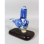 AN 18TH CENTURY PERSIAN BLUE AND WHITE POTTERY PIGEON on a wooden base, 17cm long, 13cm high.