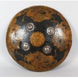 AN 18TH CENTURY INDIAN RAJASTHAN PAINTED AND LAQUERED LEATHER SHIELD, the front with four steel