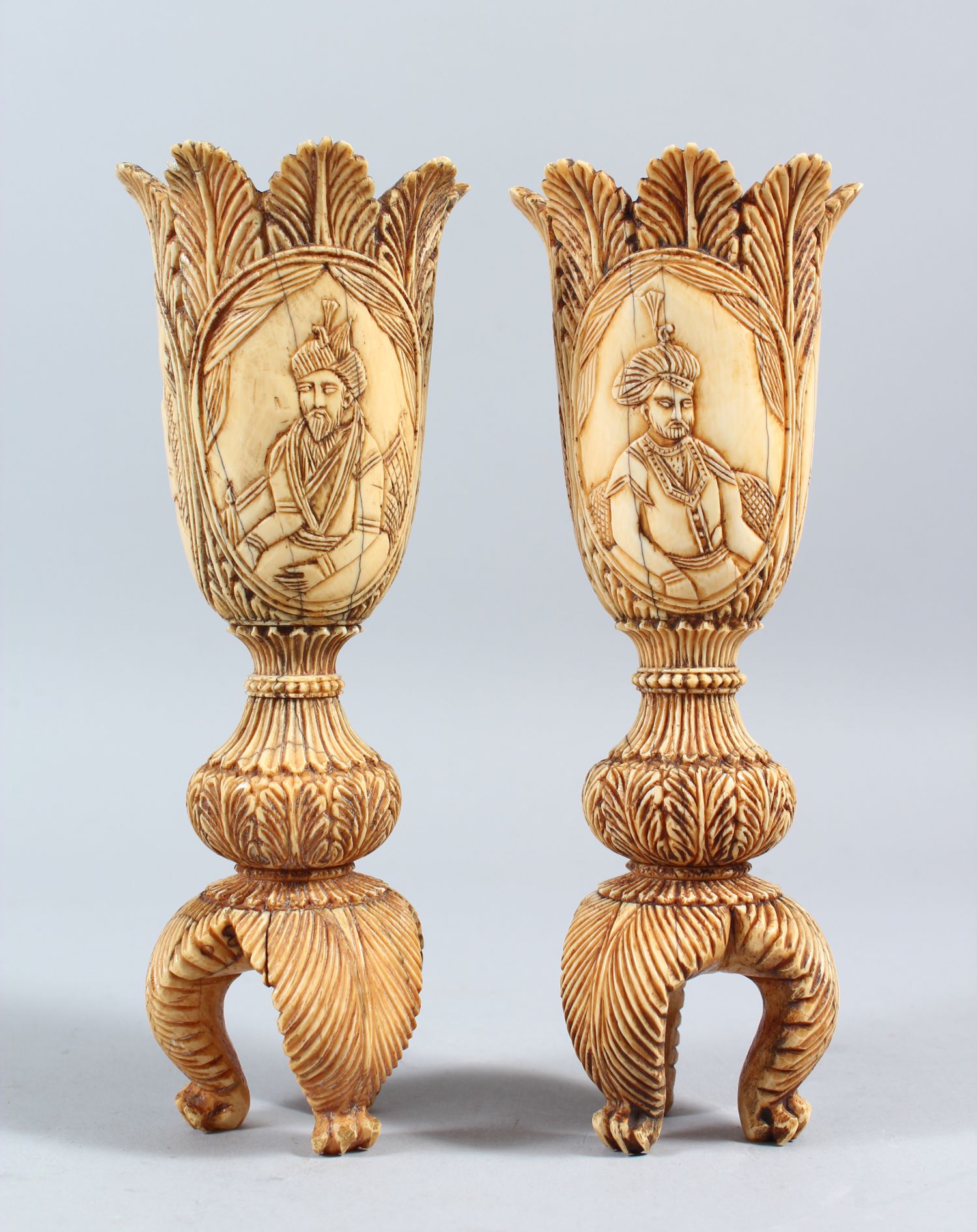 A PAIR OF 19TH CENTURY INDIAN CARVED IVORY TULIP SHAPED VASES, depicting Mughal rulers and consorts,