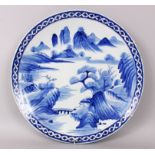 A LARGE JAPANESE IMARI BLUE AND WHITE CHARGER, with mountains, trees, bridge and buildings. 45cm