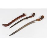 TWO 18TH-19TH CNETURY MALAYSIAN DAGGERS, with rhino horn carved handles, 40cm long.