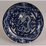 A CHINESE BLUE & WHITE PORCELAIN DRAGON DISH, of saucer shape, the decoration reserved on a blue