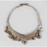 A 19TH CENTURY MALAYSIAN SILVER NECKLACE, engraved with verses from the Quran and hung with bells.