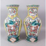 A VERY GOOD PAIR OF 19TH CENTURY FAMILLE ROSE VASES, yellow ground with panels of warriors. 46cm