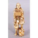 A SIGNED JAPANESE MEIJI PERIOD IVORY OKIMONO OF A STANDING STREET ENTERTAINER, the base with an
