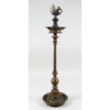 A TALL 19TH CENTURY SOUTH INDIAN BRASS CANDLESTICK with bird terminal and circular base.