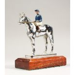 A SILVERED BRONZE MODEL OF A HORSE AND JOCKEY on a wooden base. 6.5ins high.