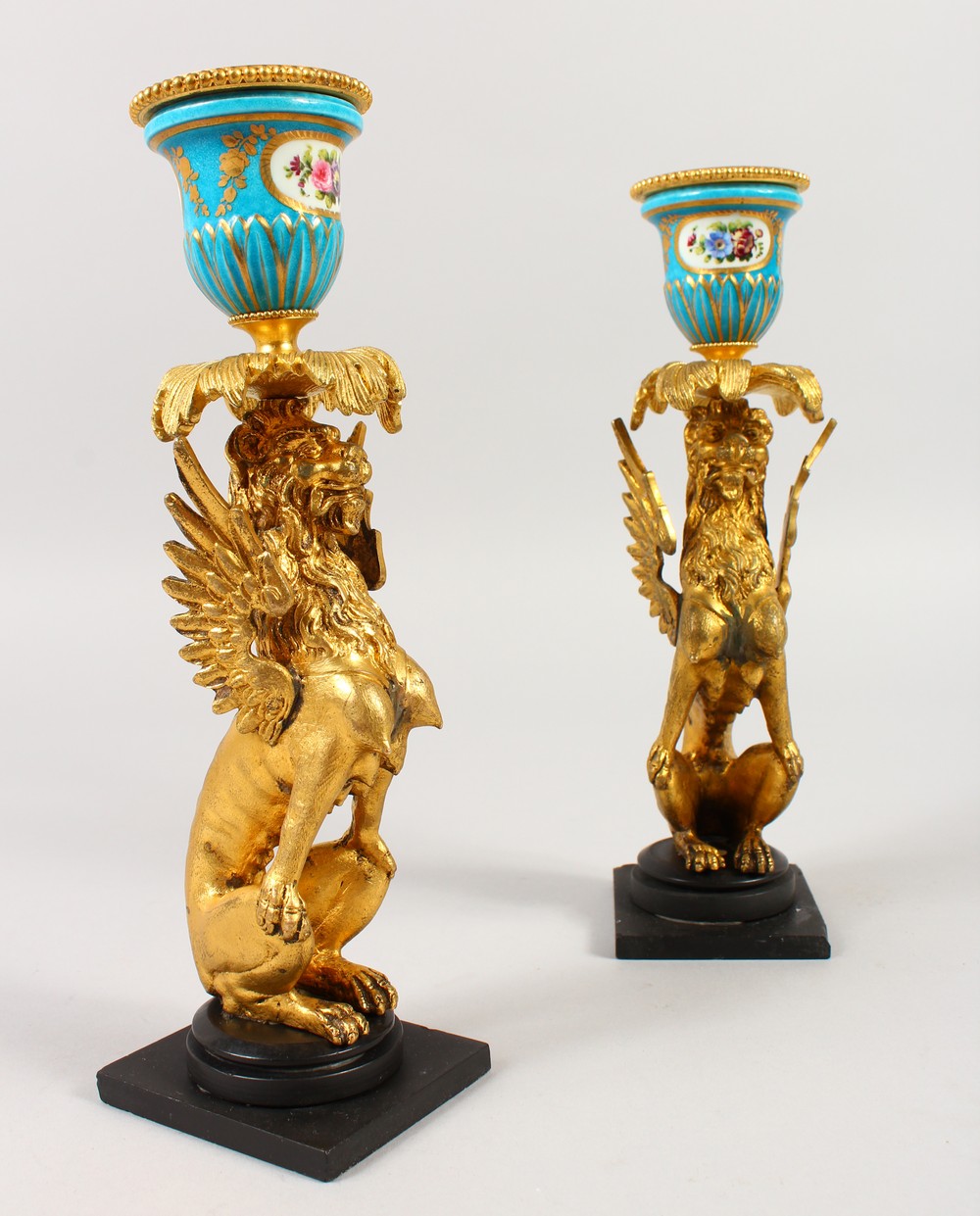 A GOOD PAIR OF FRENCH SEVRES PORCELAIN AND ORMOLU WINGED LION CANDLESTICKS. 9ins high.