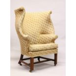 A GEORGE III MAHOGANY FRAMED LARGE WINGBACK ARMCHAIR, with loose cushions, square legs united by