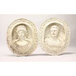 A PAIR OF CARVED AND PAINTED WOOD OVAL PLAQUES, depicting an emperor and empress busts in a grape
